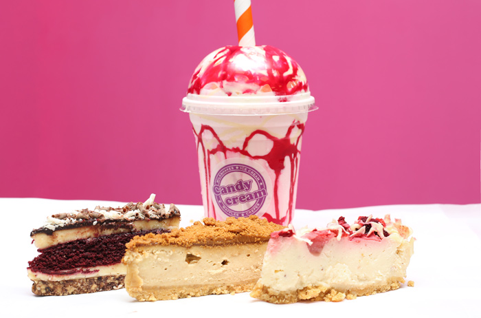 Gourmet Candy Cream milkshake topped with red syrup, surrounded by slices of red 
velvet cake and cheesecake at the Bathgate dessert shop 